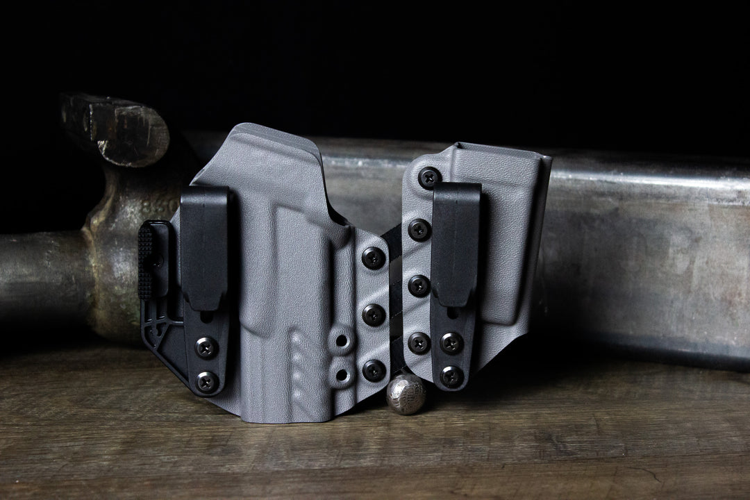 Shadow Systems MR920 inside a right-handed Entrada holster in Carbide Grey, equipped with Griphook clips and a Modwing. Holster is staged on a rugged workbench with a dark industrial backdrop.